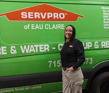 girl with black hair standing in front of a green SERVPRO van. 