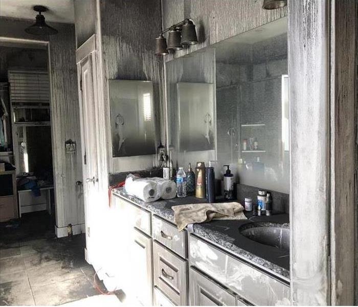 Bathroom with white cabinets damaged by fire