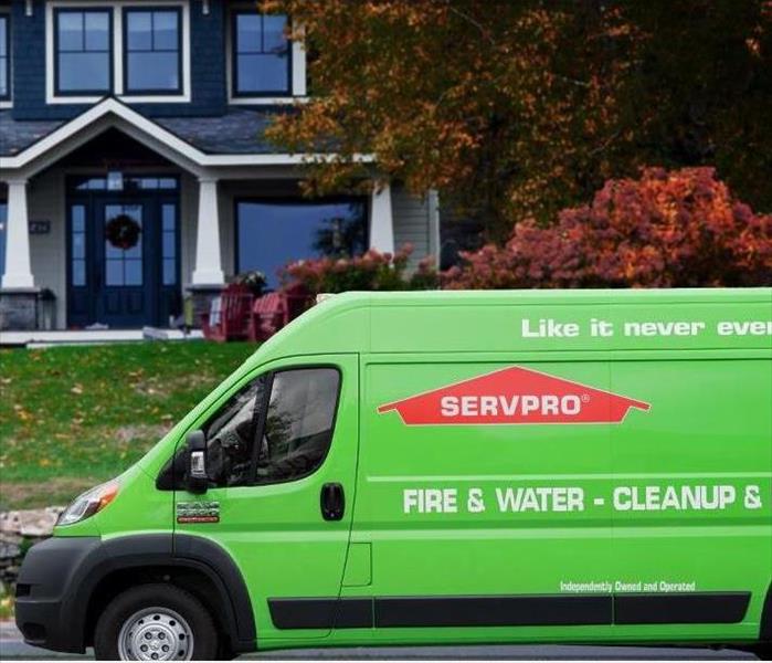 Green SERVPRO van in front of blue house